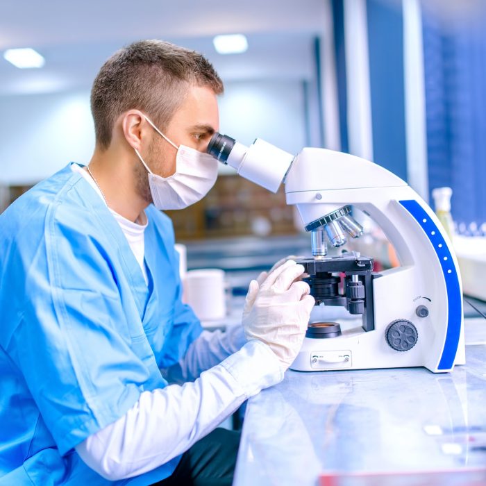 male-scientist-chemist-working-with-microscope-in-pharmaceutica